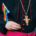 A cardinal is holding a small rainbow flag: only the flag, cross and habit are seen